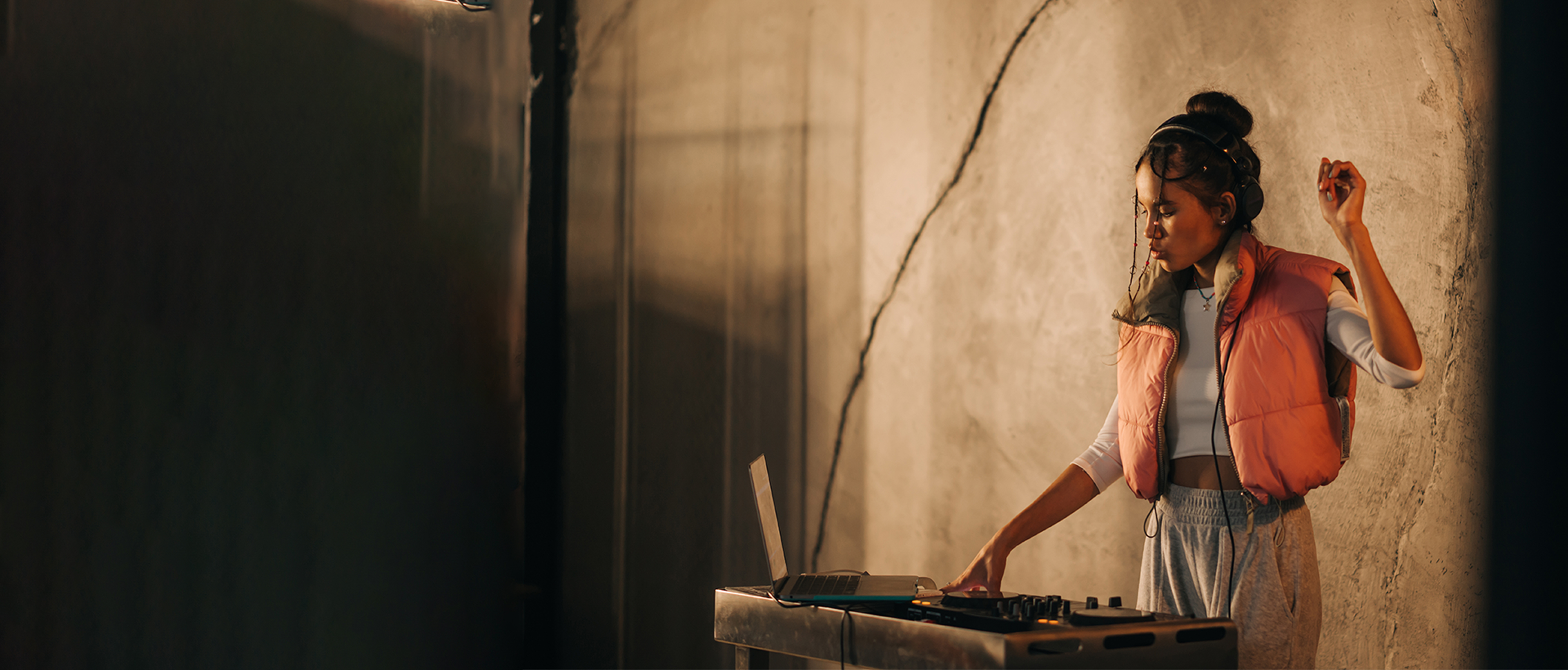 Wide banner image of a girl in an orange gilet DJing